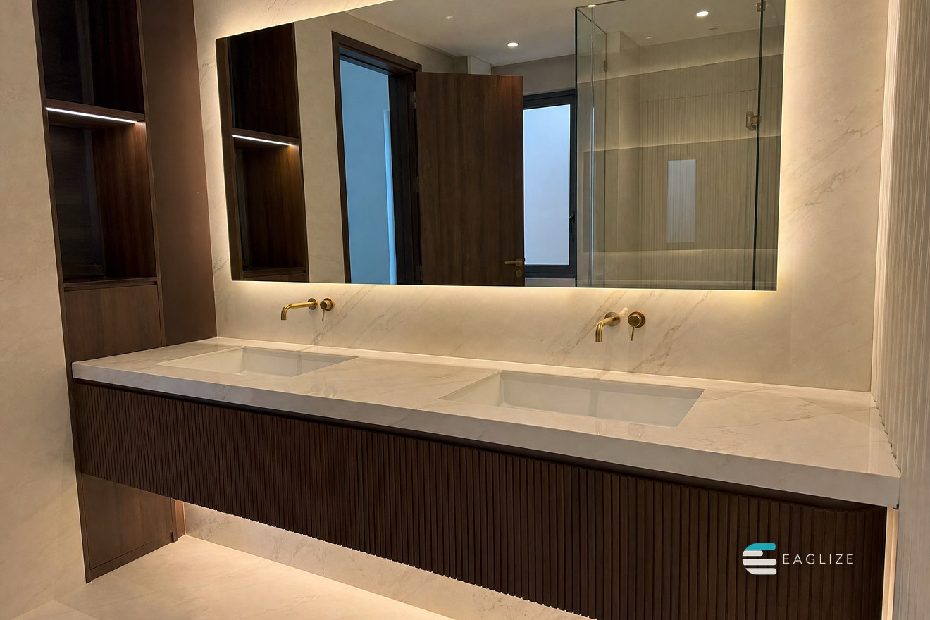 Floating double vanity in fluted timber with a stone top and a mirror backlit across the whole run