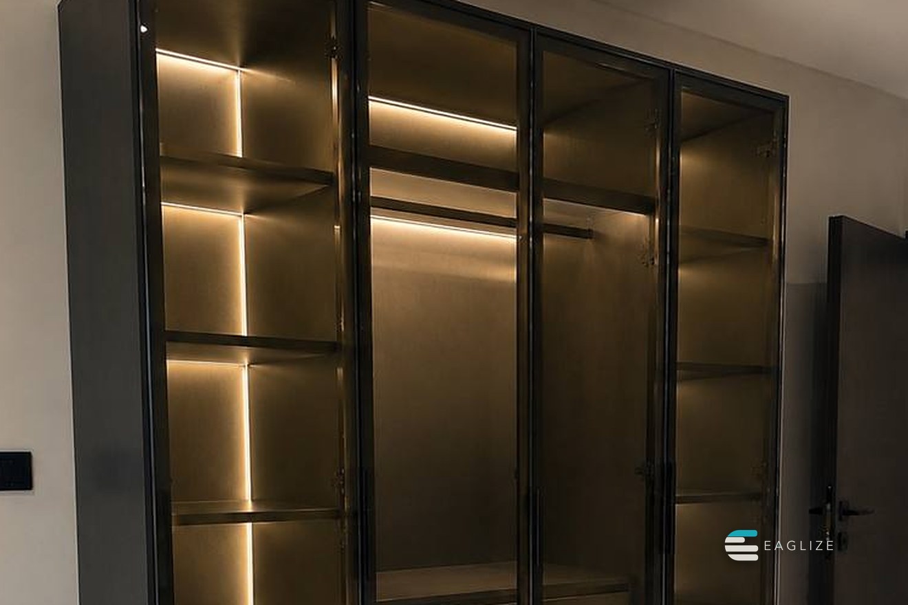 Standalone wardrobe in dark timber with smoked glass doors and lighting integrated into every shelf